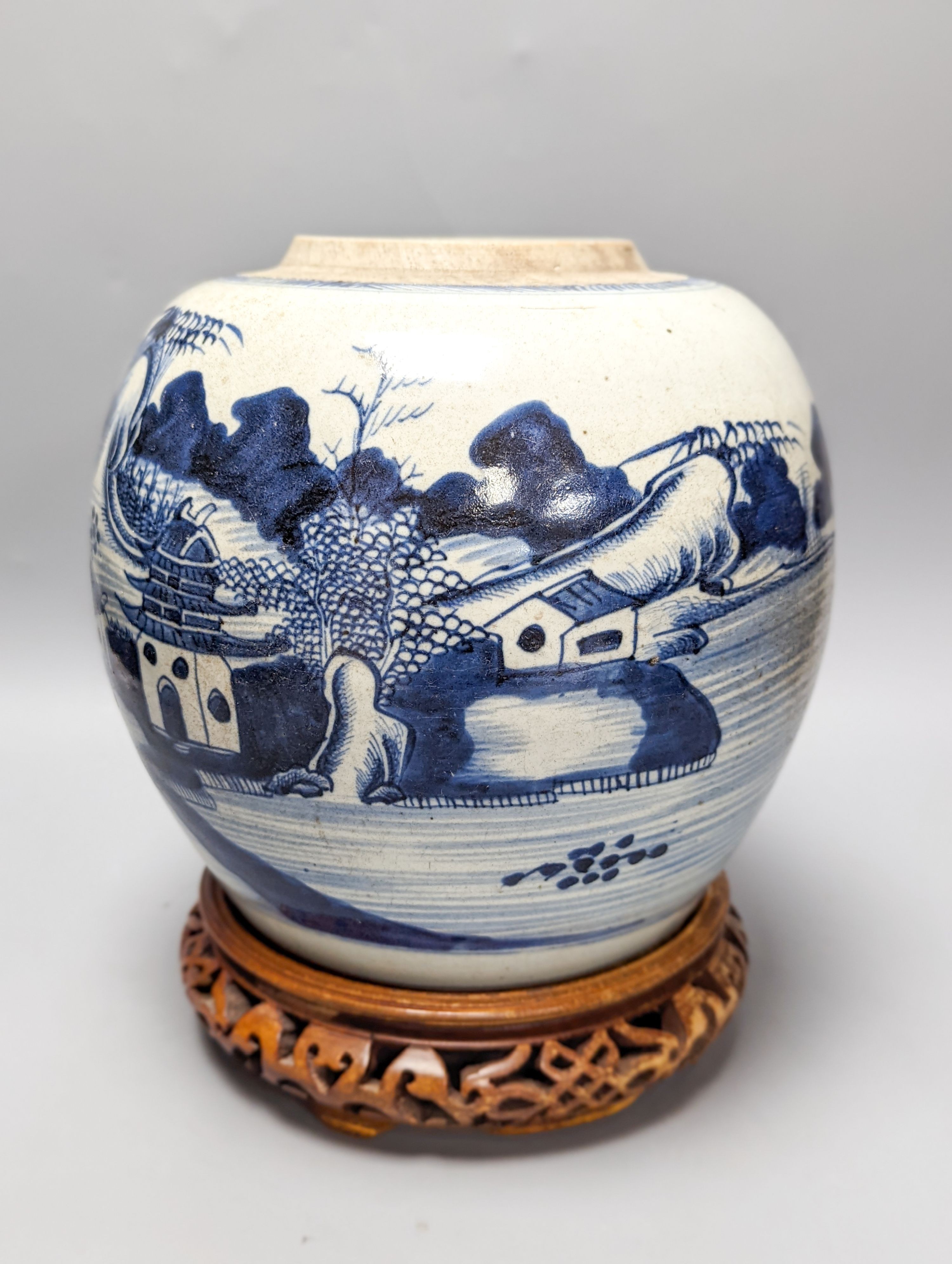 An 18th century Chinese provincial blue and white jar on a wooden stand. 25cm including stand